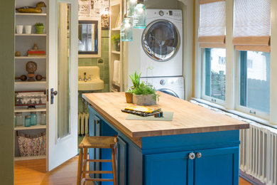 Laundry room - farmhouse laundry room idea in Chicago with open cabinets, blue cabinets, wood countertops and a stacked washer/dryer