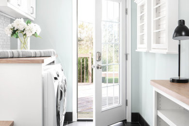 Modelo de lavadero multiusos y de galera clásico renovado con armarios con paneles empotrados, puertas de armario blancas, encimera de madera, paredes grises, lavadora y secadora juntas y suelo negro