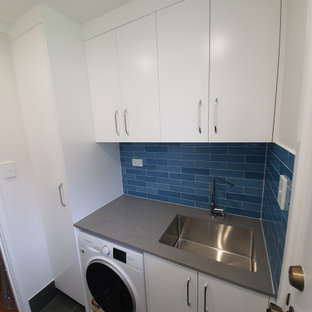 Foto di una sala lavanderia design di medie dimensioni con lavello integrato, ante lisce, ante bianche, top in quarzo composito, paraspruzzi blu, paraspruzzi con piastrelle a listelli, pareti bianche, pavimento con piastrelle in ceramica, lavatrice e asciugatrice affiancate, pavimento grigio e top grigio