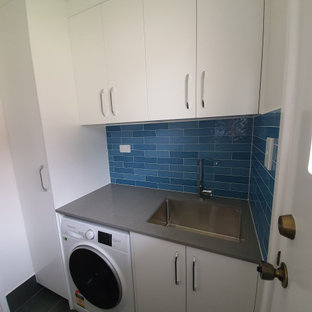 Esempio di una sala lavanderia minimal di medie dimensioni con lavello integrato, ante lisce, ante bianche, top in quarzo composito, paraspruzzi blu, paraspruzzi con piastrelle a listelli, pareti bianche, pavimento con piastrelle in ceramica, lavatrice e asciugatrice affiancate, pavimento grigio e top grigio