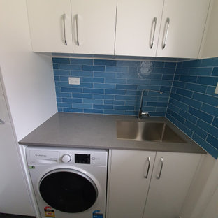 Idee per una sala lavanderia contemporanea di medie dimensioni con lavello integrato, ante lisce, ante bianche, top in quarzo composito, paraspruzzi blu, paraspruzzi con piastrelle a listelli, pareti bianche, pavimento con piastrelle in ceramica, lavatrice e asciugatrice affiancate, pavimento grigio e top grigio