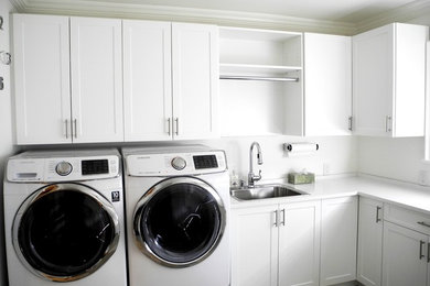 Diseño de lavadero en U actual de tamaño medio con fregadero encastrado, armarios estilo shaker, puertas de armario blancas, paredes blancas, lavadora y secadora juntas y encimeras blancas