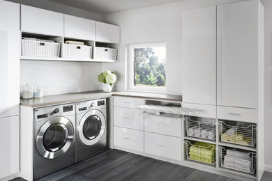 Large trendy l-shaped medium tone wood floor and gray floor laundry room photo in Miami with flat-panel cabinets, white cabinets, laminate countertops, gray walls and a side-by-side washer/dryer
