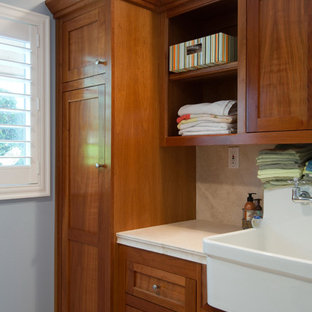 Immagine di una sala lavanderia minimalista di medie dimensioni con lavello stile country, ante in stile shaker, ante in legno scuro, top in pietra calcarea, pareti blu e lavatrice e asciugatrice affiancate