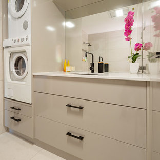 Esempio di una lavanderia multiuso contemporanea di medie dimensioni con top in quarzo composito, pavimento in gres porcellanato, lavatrice e asciugatrice a colonna, pavimento beige, lavello sottopiano, ante lisce, ante beige, pareti beige e top bianco