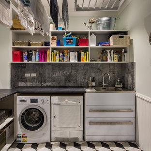 Ispirazione per una grande sala lavanderia vittoriana con lavatoio, top in granito, pareti blu, pavimento in gres porcellanato e lavatrice e asciugatrice affiancate