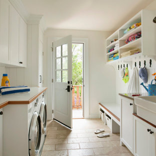 Exempel på ett mellanstort klassiskt parallellt grovkök, med en rustik diskho, luckor med infälld panel, vita skåp, laminatbänkskiva, vita väggar, kalkstensgolv, en tvättmaskin och torktumlare bredvid varandra och beiget golv