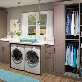 Inspiration for a large transitional single-wall laminate floor dedicated laundry room remodel in Charleston with a drop-in sink, flat-panel cabinets, brown cabinets, solid surface countertops, gray walls and a side-by-side washer/dryer