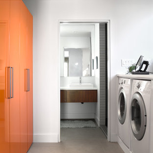Idéer för att renovera en 50 tals vita parallell vitt tvättstuga enbart för tvätt, med släta luckor, orange skåp, vita väggar och en tvättmaskin och torktumlare bredvid varandra