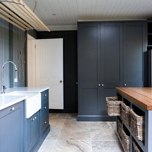Idee per una grande sala lavanderia tradizionale con lavello stile country, ante in stile shaker, ante grigie, top in marmo, paraspruzzi bianco, paraspruzzi in gres porcellanato, pavimento in travertino, pareti grigie e lavatrice e asciugatrice nascoste