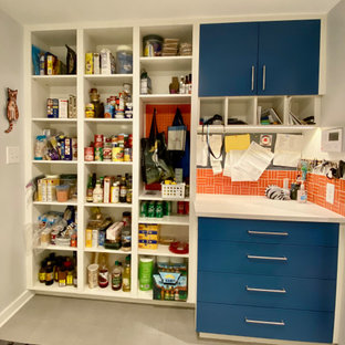 Foto på en funkis vita tvättstuga, med en allbänk, släta luckor, blå skåp, laminatbänkskiva, orange stänkskydd, stänkskydd i keramik, vita väggar, klinkergolv i porslin, en tvättmaskin och torktumlare bredvid varandra och grått golv