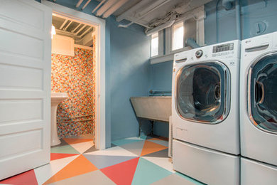 Modelo de cuarto de lavado contemporáneo grande con fregadero sobremueble, paredes azules, lavadora y secadora juntas y suelo de cemento