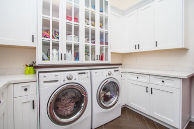 Mid-sized transitional u-shaped ceramic tile and gray floor dedicated laundry room photo in Phoenix with shaker cabinets, white cabinets, solid surface countertops, white walls, a side-by-side washer/dryer and an undermount sink
