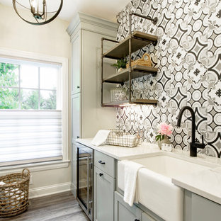 Foto di una lavanderia multiuso country di medie dimensioni con lavello stile country, ante in stile shaker, ante grigie, top in quarzite, pareti beige, pavimento in vinile, lavatrice e asciugatrice affiancate, pavimento multicolore e top bianco