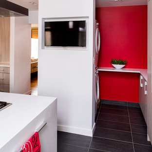 Esempio di una piccola sala lavanderia minimal con ante lisce, ante in legno chiaro, top in quarzo composito, pareti rosse, pavimento in gres porcellanato, lavatrice e asciugatrice a colonna e pavimento grigio