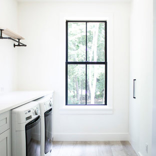Esempio di una sala lavanderia nordica di medie dimensioni con lavello sottopiano, ante in stile shaker, ante bianche, top in quarzo composito, pareti bianche, pavimento in vinile, lavatrice e asciugatrice affiancate e top bianco