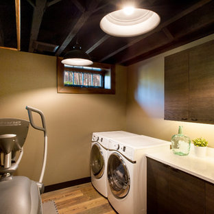 Idée de décoration pour une buanderie chalet de taille moyenne avec un évier encastré, un placard à porte plane, des portes de placard en bois sombre, un plan de travail en quartz, un mur beige, un sol en bois foncé et des machines côte à côte.