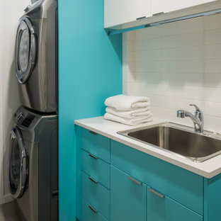 Esempio di una sala lavanderia minimalista di medie dimensioni con lavello da incasso, ante lisce, ante turchesi, top in quarzite, pareti bianche, pavimento in gres porcellanato, lavatrice e asciugatrice a colonna, pavimento grigio e top bianco