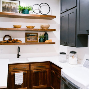 Immagine di una lavanderia rustica con lavello sottopiano, ante in legno bruno, top in quarzo composito, paraspruzzi bianco, paraspruzzi con piastrelle in ceramica, pareti bianche, pavimento con piastrelle in ceramica, lavatrice e asciugatrice affiancate, pavimento grigio e top bianco