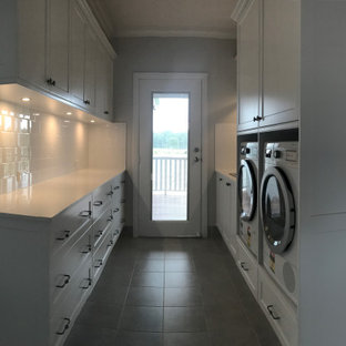 Ispirazione per una sala lavanderia country di medie dimensioni con lavello da incasso, ante in stile shaker, ante bianche, top in quarzo composito, paraspruzzi bianco, paraspruzzi con piastrelle in ceramica, pareti grigie, pavimento con piastrelle in ceramica, lavatrice e asciugatrice affiancate, pavimento grigio e top bianco