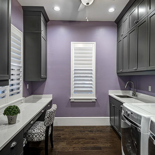 Esempio di una grande lavanderia multiuso american style con lavello sottopiano, ante con riquadro incassato, ante grigie, top in quarzite, pareti viola, parquet scuro e lavatrice e asciugatrice affiancate