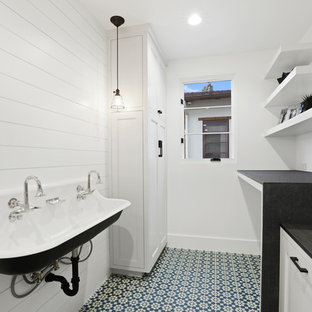 Idee per una piccola sala lavanderia minimalista con lavatoio, pareti bianche, pavimento in cemento, lavatrice e asciugatrice affiancate, pavimento blu, ante con riquadro incassato e ante bianche