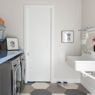 Inspiration för moderna parallella blått tvättstugor enbart för tvätt, med en allbänk, beige väggar, en tvättmaskin och torktumlare bredvid varandra och flerfärgat golv
