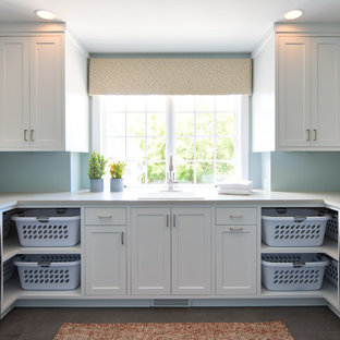 Ispirazione per una grande sala lavanderia tradizionale con lavello da incasso, ante in stile shaker, ante bianche, top in onice, pareti blu, lavatrice e asciugatrice affiancate, pavimento grigio e top bianco