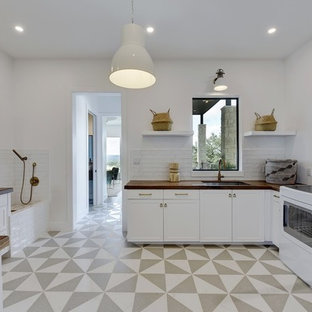 Foto di un'ampia lavanderia multiuso nordica con lavello sottopiano, ante in stile shaker, ante bianche, top in legno, pareti bianche, pavimento in gres porcellanato, lavatrice e asciugatrice affiancate, pavimento multicolore e top marrone
