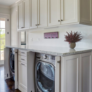 Immagine di una lavanderia multiuso chic di medie dimensioni con lavello stile country, ante in stile shaker, ante bianche, top in granito, pareti bianche, parquet scuro, lavatrice e asciugatrice nascoste, pavimento marrone e top multicolore