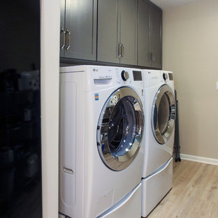 Exemple d'une buanderie linéaire chic multi-usage et de taille moyenne avec un placard à porte shaker, des portes de placard grises, un mur beige, un sol en vinyl, des machines côte à côte et un sol marron.