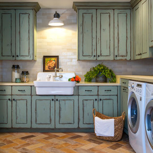 Inspiration for a large mediterranean terra-cotta tile and multicolored floor dedicated laundry room remodel in Phoenix with a farmhouse sink, raised-panel cabinets, green cabinets, concrete countertops, white walls and a side-by-side washer/dryer