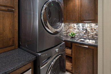 Example of a mid-sized trendy laundry room design in Orange County with an undermount sink, medium tone wood cabinets, quartz countertops, a stacked washer/dryer and gray walls