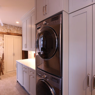 Immagine di una lavanderia multiuso country di medie dimensioni con lavello stile country, ante con riquadro incassato, top in granito, pareti beige, pavimento in gres porcellanato, lavatrice e asciugatrice a colonna, pavimento marrone, top verde e ante grigie