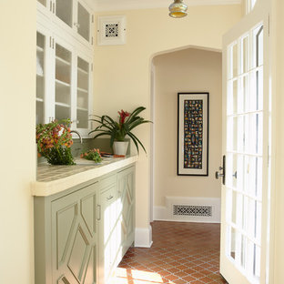 Idee per una lavanderia multiuso tradizionale con lavello sottopiano, ante con riquadro incassato, ante verdi, top piastrellato, pavimento in terracotta, lavatrice e asciugatrice nascoste e pareti beige