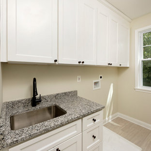 Exemple d'une buanderie linéaire craftsman dédiée et de taille moyenne avec un évier encastré, un placard à porte shaker, des portes de placard blanches, un plan de travail en granite, un mur beige, un sol en carrelage de céramique, des machines côte à côte et un sol beige.