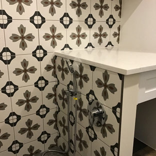 Foto di una piccola lavanderia multiuso bohémian con ante in stile shaker, ante bianche, top in quarzo composito, paraspruzzi bianco, paraspruzzi in gres porcellanato, pareti grigie, pavimento in gres porcellanato, lavatrice e asciugatrice a colonna, pavimento marrone e top bianco