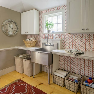 Foto di una sala lavanderia country con lavatoio, ante con riquadro incassato, ante bianche, pareti rosse e parquet chiaro