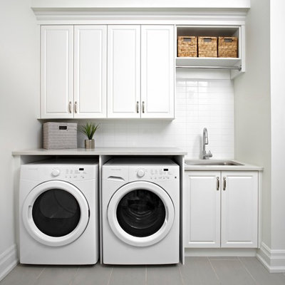 Laundry room - traditional single-wall laundry room idea in Toronto with an undermount sink, raised-panel cabinets, white cabinets, white walls, a side-by-side washer/dryer and gray countertops