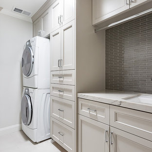 Example of a transitional single-wall laundry room design in San Francisco with an undermount sink, beige cabinets, marble countertops, gray walls, a stacked washer/dryer, white countertops and recessed-panel cabinets