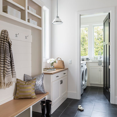Inspiration for a mid-sized timeless single-wall ceramic tile and black floor utility room remodel in Minneapolis with white cabinets, laminate countertops, white walls, a side-by-side washer/dryer and shaker cabinets