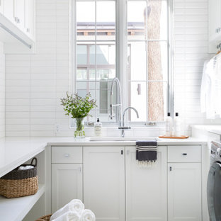 Ispirazione per una lavanderia multiuso mediterranea con lavello sottopiano, ante in stile shaker, ante bianche, pareti bianche, pavimento con piastrelle in ceramica, pavimento beige e top bianco