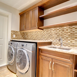 Idée de décoration pour une buanderie linéaire craftsman dédiée et de taille moyenne avec un évier encastré, un placard à porte affleurante, des portes de placard en bois brun, un plan de travail en quartz modifié, un mur beige, un sol en carrelage de céramique, des machines côte à côte et un sol beige.