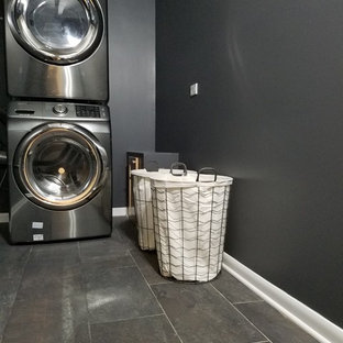 Exempel på en mellanstor modern tvättstuga enbart för tvätt, med svarta väggar, vinylgolv, en tvättpelare och brunt golv