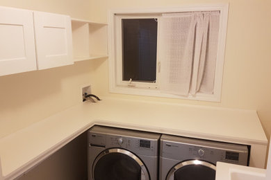Modelo de cuarto de lavado en L actual pequeño con armarios estilo shaker, encimera de madera y encimeras blancas