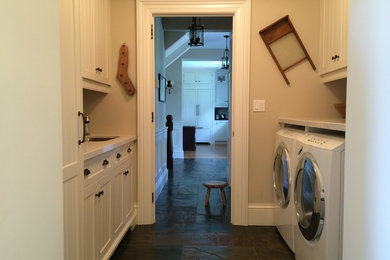 Dedicated laundry room - traditional galley slate floor dedicated laundry room idea in Toronto with an undermount sink, flat-panel cabinets, white cabinets, beige walls and a side-by-side washer/dryer