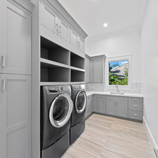 Idee per una grande sala lavanderia classica con lavello sottopiano, ante in stile shaker, ante grigie, top in quarzite, pareti bianche, pavimento in gres porcellanato, lavatrice e asciugatrice affiancate, pavimento beige e top bianco