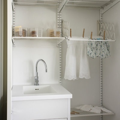 Inspiration for a small contemporary single-wall light wood floor dedicated laundry room remodel in Barcelona with white cabinets, white walls, a side-by-side washer/dryer and an integrated sink