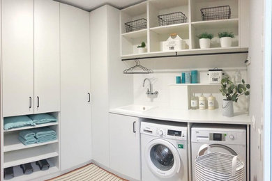 Imagen de cuarto de lavado en L contemporáneo de tamaño medio con puertas de armario blancas, encimera de madera y encimeras blancas