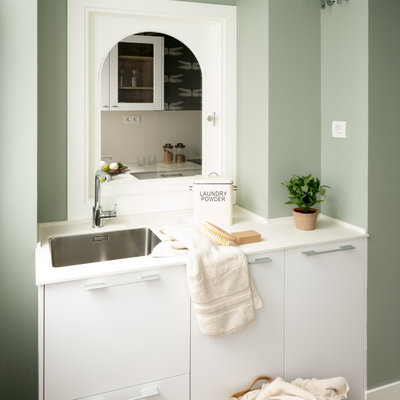 Dedicated laundry room - mid-sized scandinavian single-wall laminate floor dedicated laundry room idea in Bilbao with an undermount sink, flat-panel cabinets, white cabinets, quartz countertops, green walls, a concealed washer/dryer and white countertops